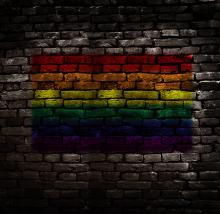 A rainbow flag painted on a dark brick wall